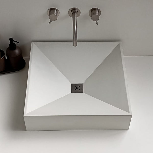 Unrefined Crux Concrete Sink – handcrafted square basin with customizable metal drain cover, installed in a modern bathroom setting.