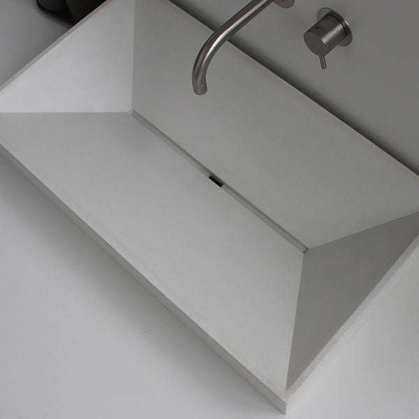 Modern handcrafted concrete sink by Unrefined with geometric basin design in light gray. With Vola faucet.